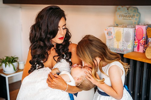 flower girl kissing baby while bride holds her