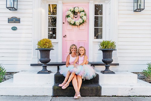 mom and daughter wearing tutus in front of pink door
