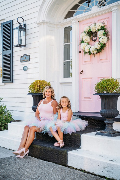 mom and daughter sitting in front of pink door