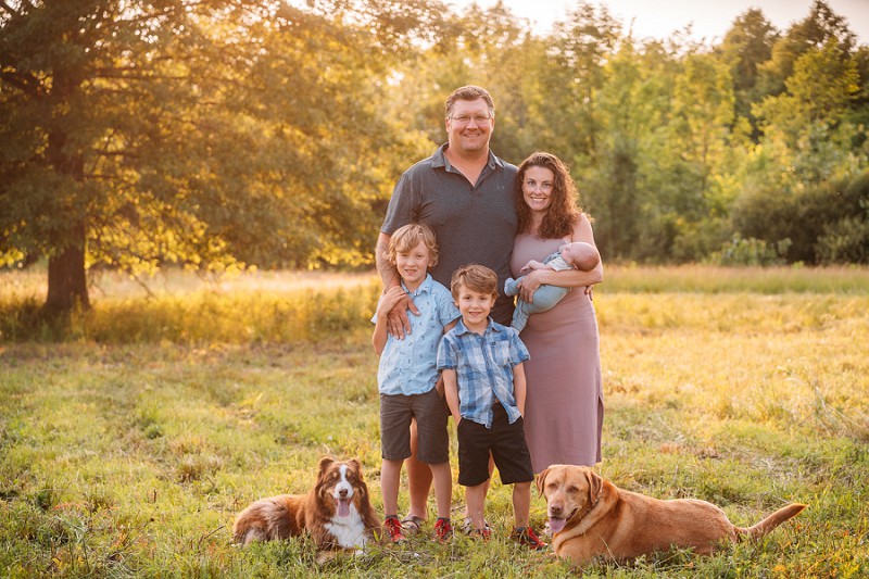 family portrait with dogs and baby at sunset