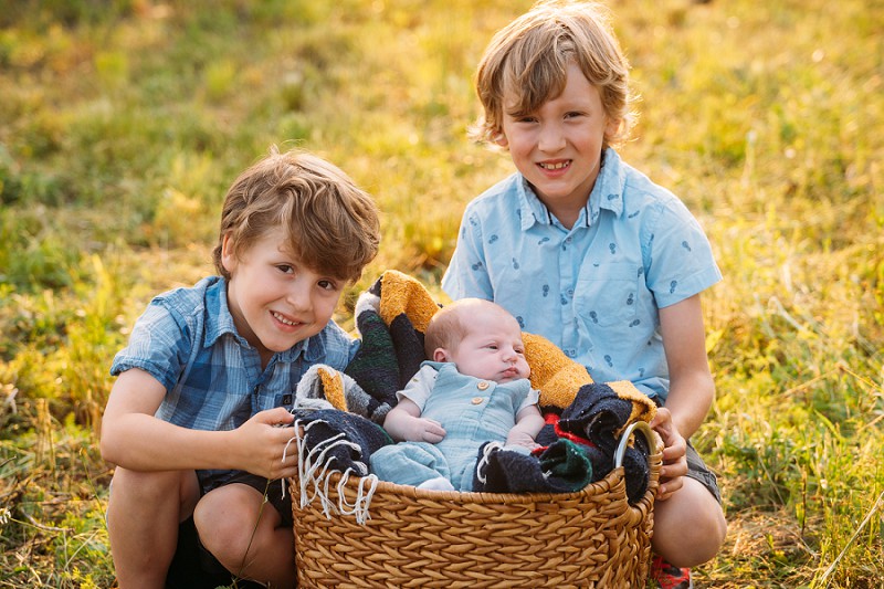 brothers smiling with newborn