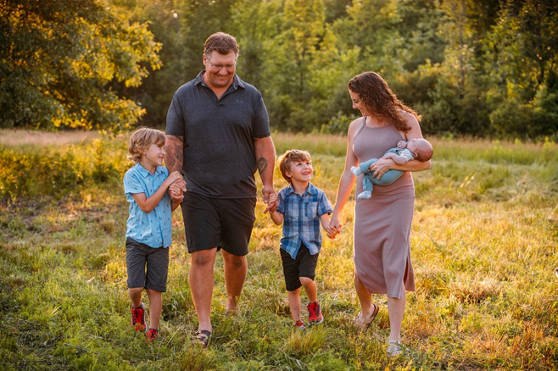 family walking through field at sunset