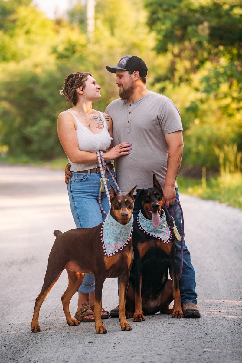 couple looking at each other with dobermans looking at camera