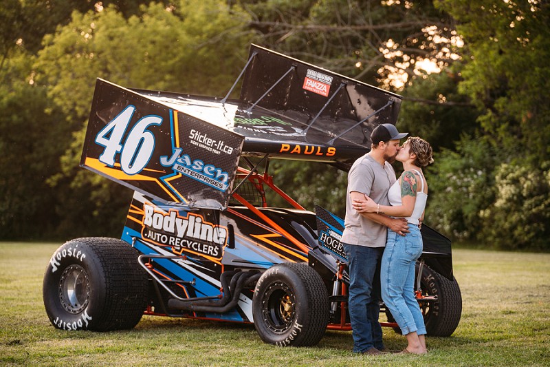 couple kissing with race car in background