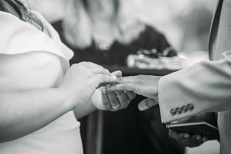 bride putting ring on grooms finger during ceremony