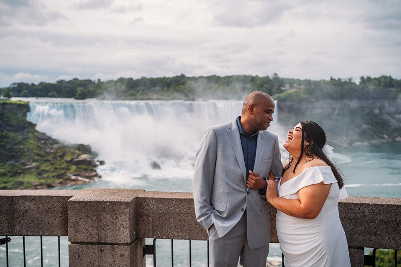 bride and groom in front of niagara falls smiling