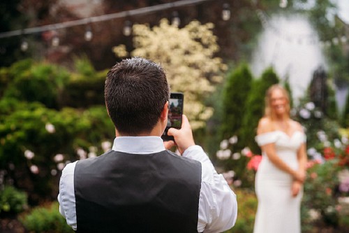 groom taking photo of his bride with phone