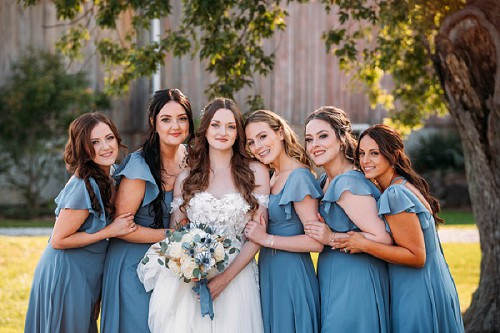 bridesmaids posing in front of barn