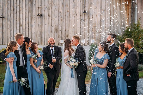 bride and groom kissing in front of kehoe and kin barn with confetti