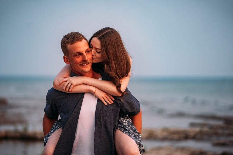 engagement shoot where guy is giving fiance a piggy back ride and she is kissing him