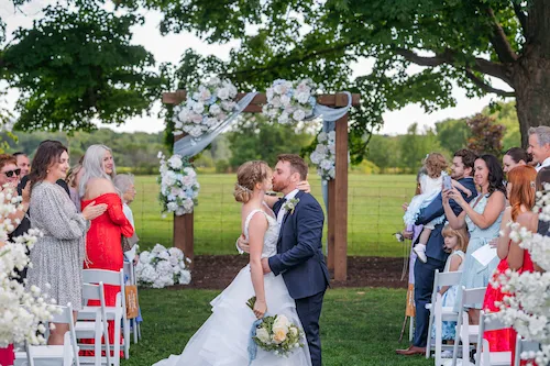 bride and groom stopping to kiss while walking down the aisle after ceremony