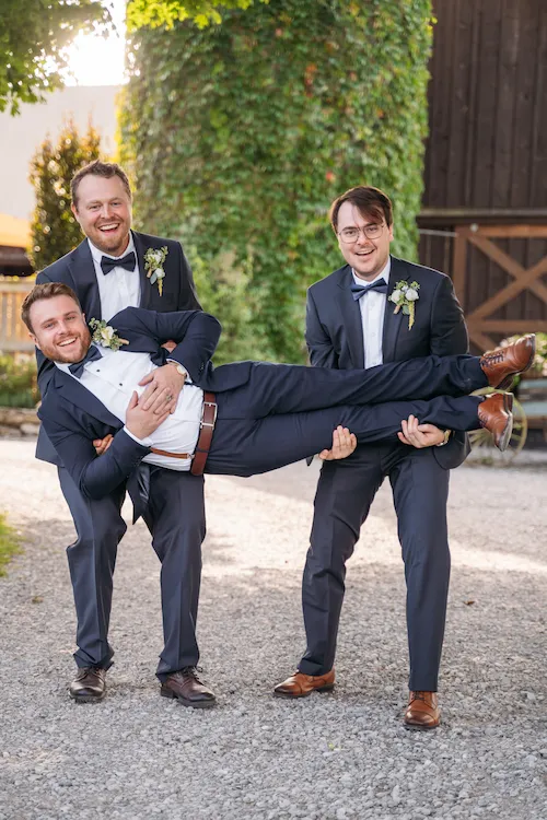 Groomsmen lifting groom for a fun wedding party photo at Maple Meadows Farm
