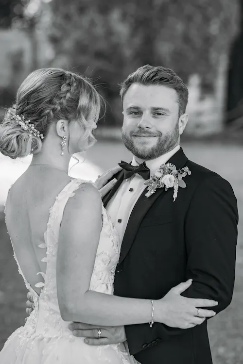 Romantic black and white of groom holding bride and staring at camera in the gardens at Maple Meadows in Port Colborne