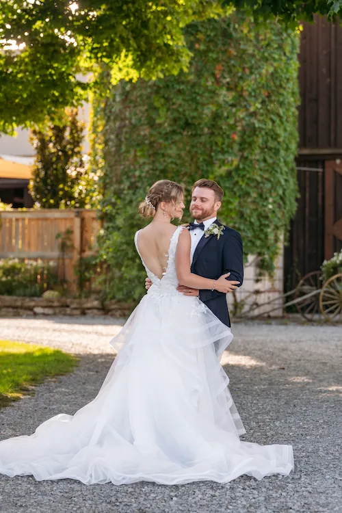 Groom holding bride and showing off back of her wedding dress at Maple Meadows in Port Colborne