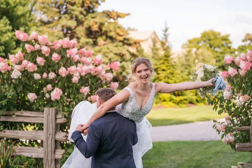 Fun moment where groom lifts bride and she is cheering