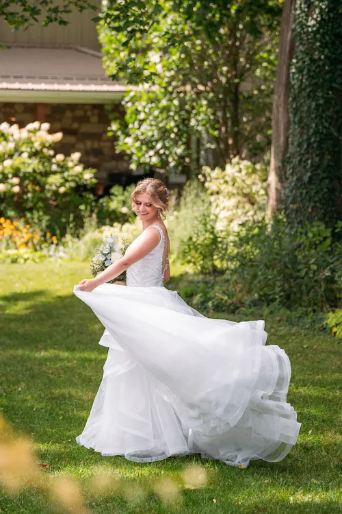 Bride playing with her dress outside in the gardens at Maple Meadows Farm
