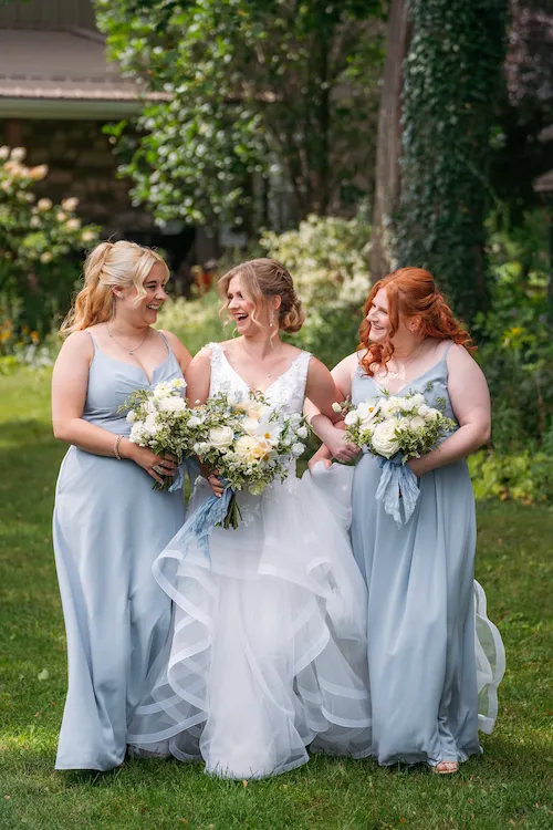 bride and bridesmaids walking and laughing in Maple Meadows Farm gardens