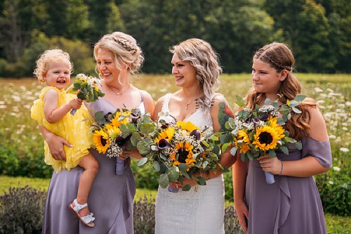 bridesmaids smiling at flower girl
