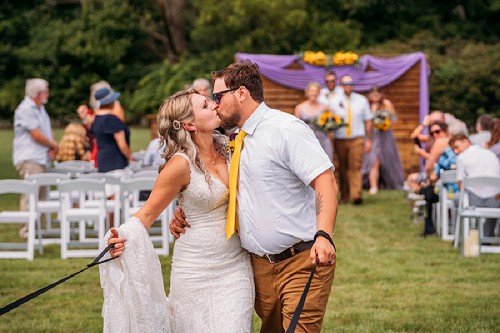 bride and groom kissing while walking down isle