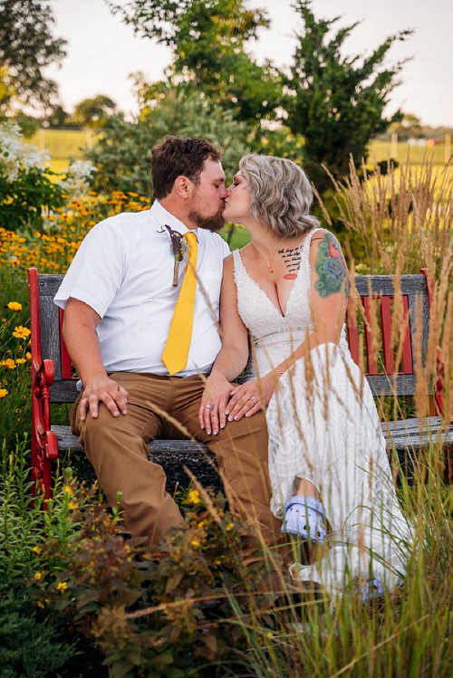 bride and groom kissing while sitting on bench
