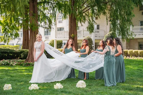 bridesmaids helping bride with dress in front of the madison hotel, nj