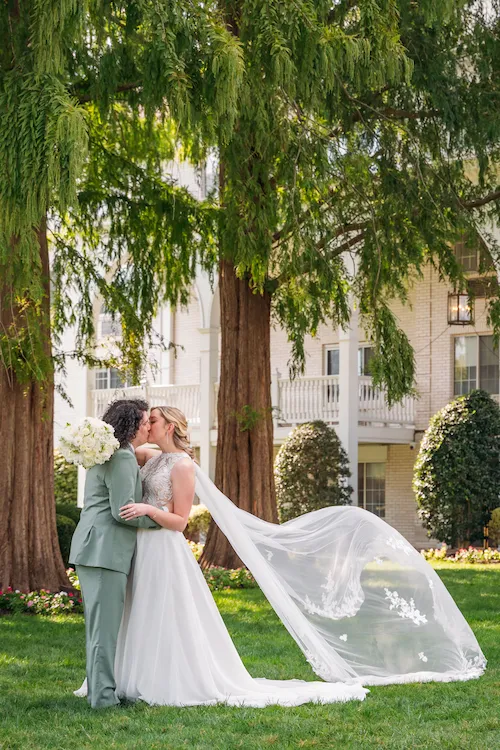 veil blowing in wind while bride and groom kiss