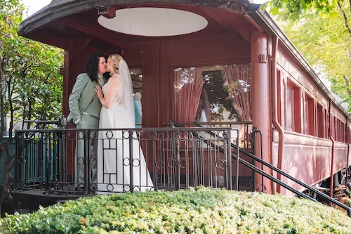 bride and groom kissing outside vintage train car at the madison