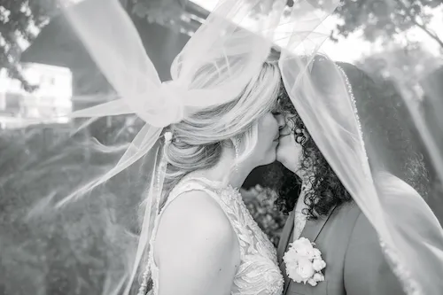 black and white of bride and groom surrounded by veil