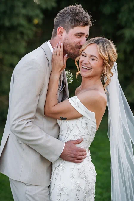 bride laughing while groom kisses her cheek at sue ann estate winery wedding photos