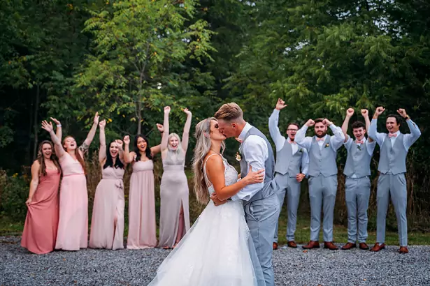 bride and groom kissing in front of wedding party