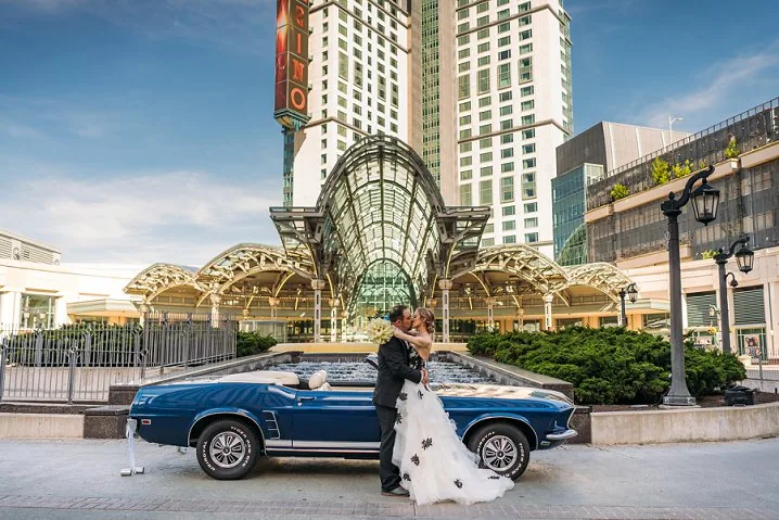 bride and groom standing infront of fallsview casino with a vintage car