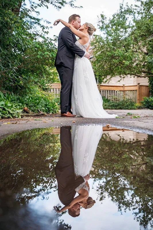 bride and groom kissing with reflection in the puddle in niagara on the lake